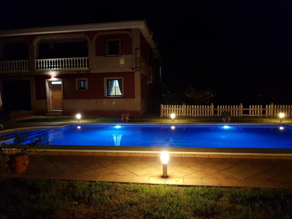 a pool with lights in front of a house at night at El Manantial B&B in El Higuerón