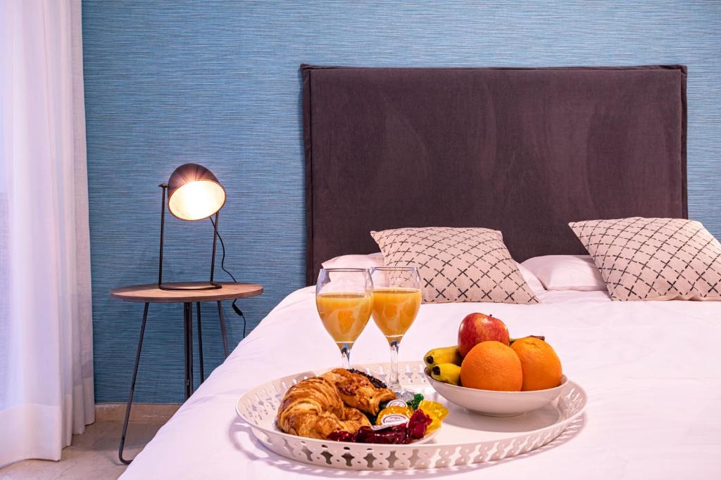マラガにあるMálaga Central Suitesのベッドの上に食べ物のトレイ(オレンジジュース2杯付)
