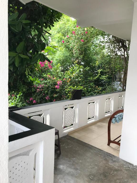 a balcony with chairs and pink flowers and trees at Unawatuna Beach Bungalow - in Unawatuna