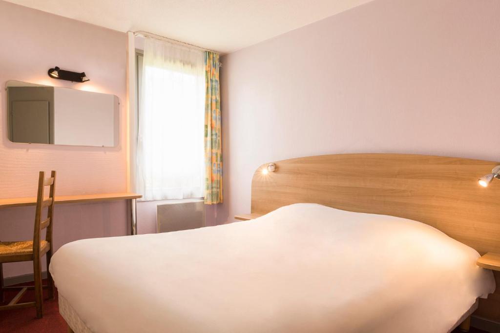 a bedroom with a bed and a desk and a window at The Originals City, Hôtel Valence Est in Valence