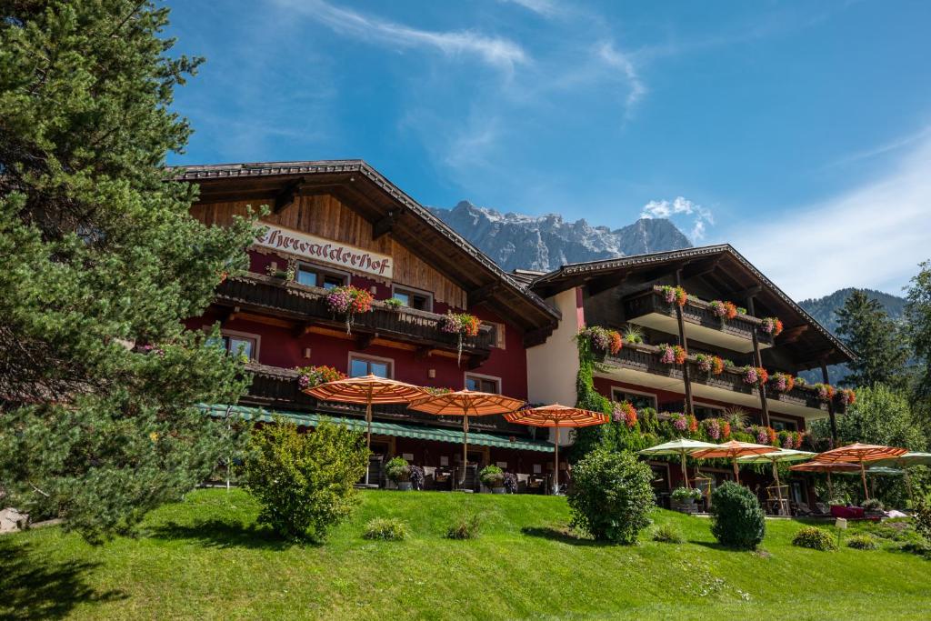 a hotel in the mountains with umbrellas in front of it at Hotel Ehrwalderhof in Ehrwald