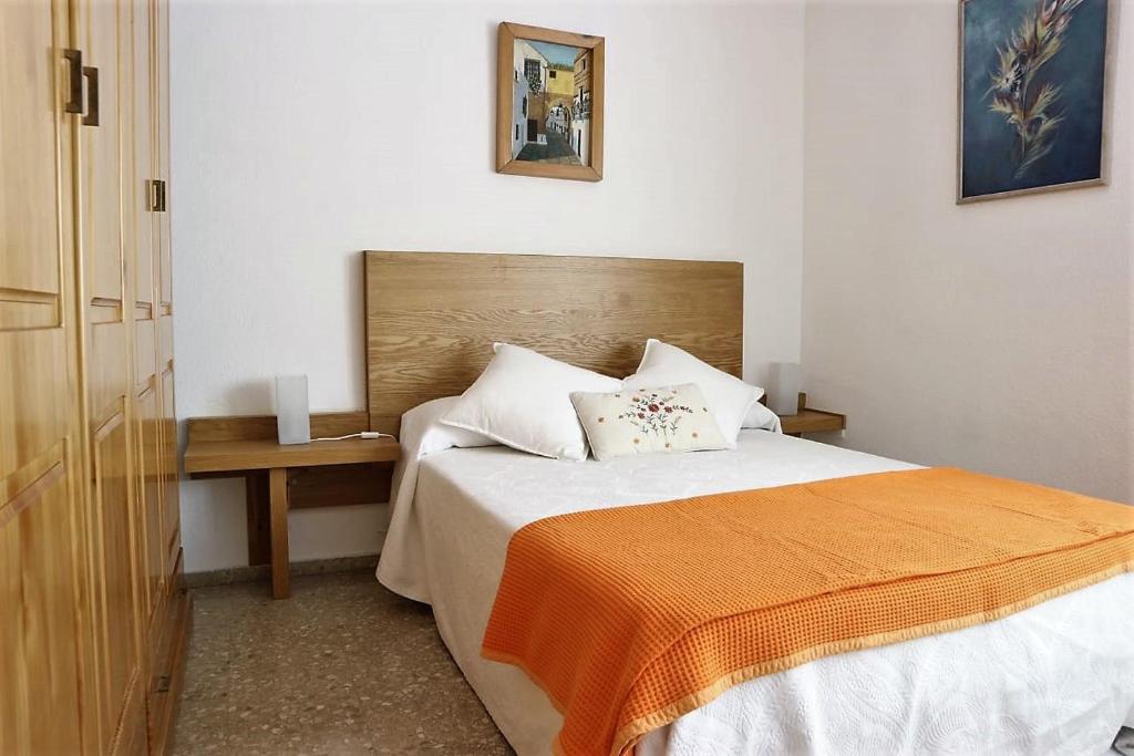 コルドバにあるAlojamiento de Remediosのベッドルーム1室(オレンジ色の毛布とテーブル付きのベッド1台付)
