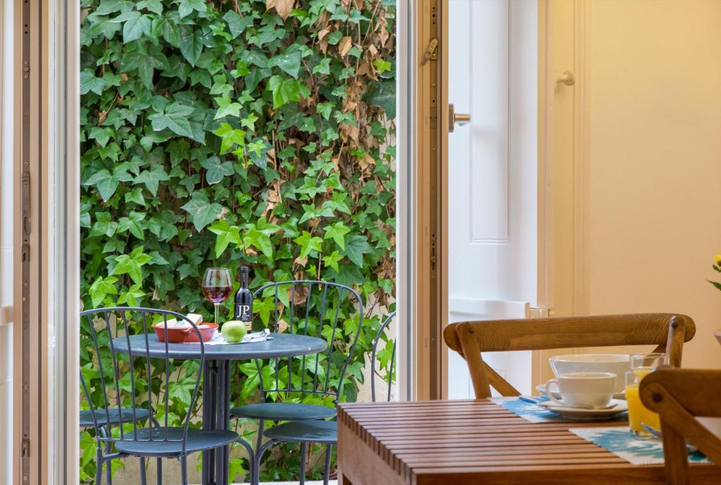 リスボンにあるPrincipe Real Patio Houseの緑の壁のパティオ(テーブル、椅子付)