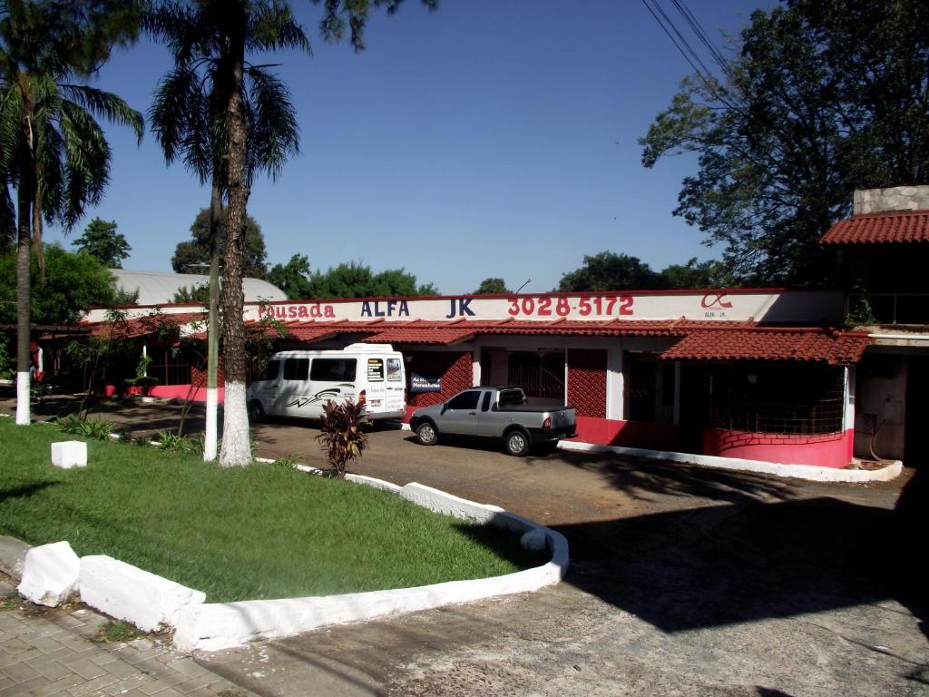 a building with cars parked in a parking lot at Pousada JK in Foz do Iguaçu