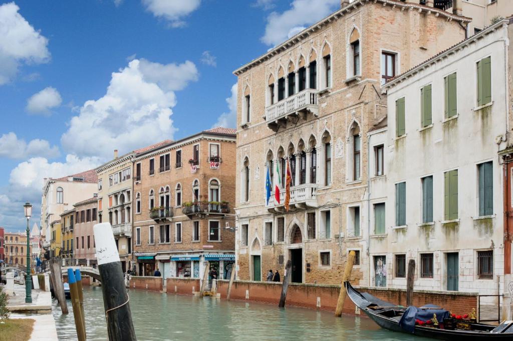 a canal with buildings and a boat in the water at Hotel Nani Mocenigo Palace in Venice