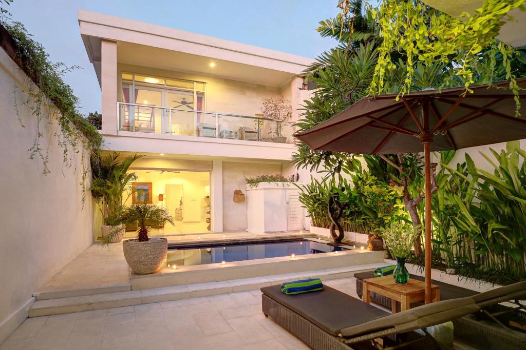 a house with a swimming pool and an umbrella at Villa Lamac in Legian
