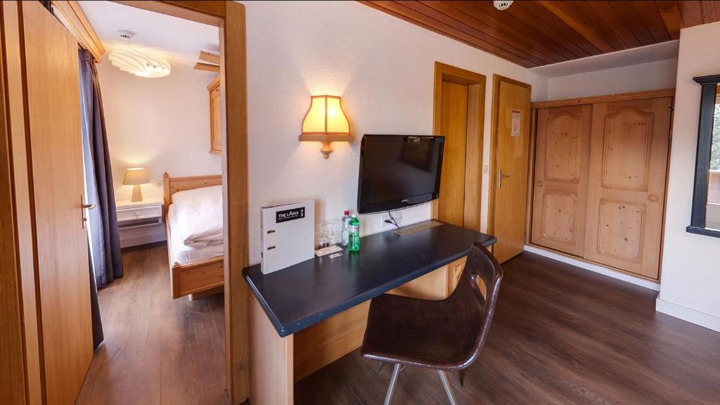a room with a desk with a television and a bed at Hotel THE LARIX ski-in ski-out in Saas-Fee