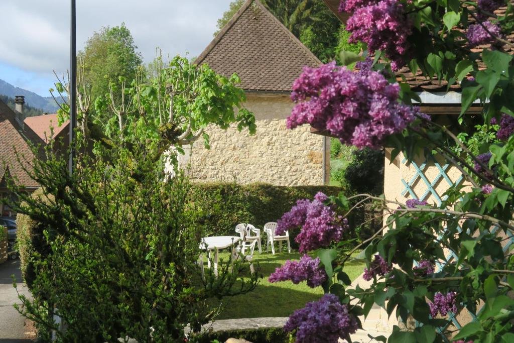 um jardim com flores roxas, mesas e cadeiras em LA FRACELINE em Saint-Pierre-dʼEntremont