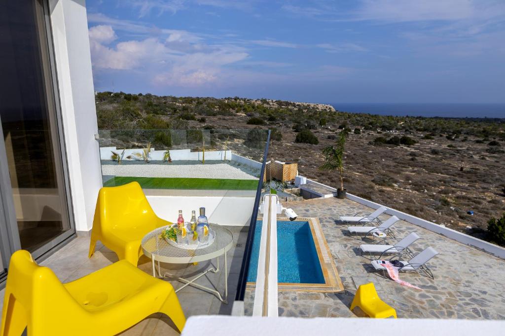 a balcony with yellow chairs and a swimming pool at Protaras Greco Hilltop Views in Protaras