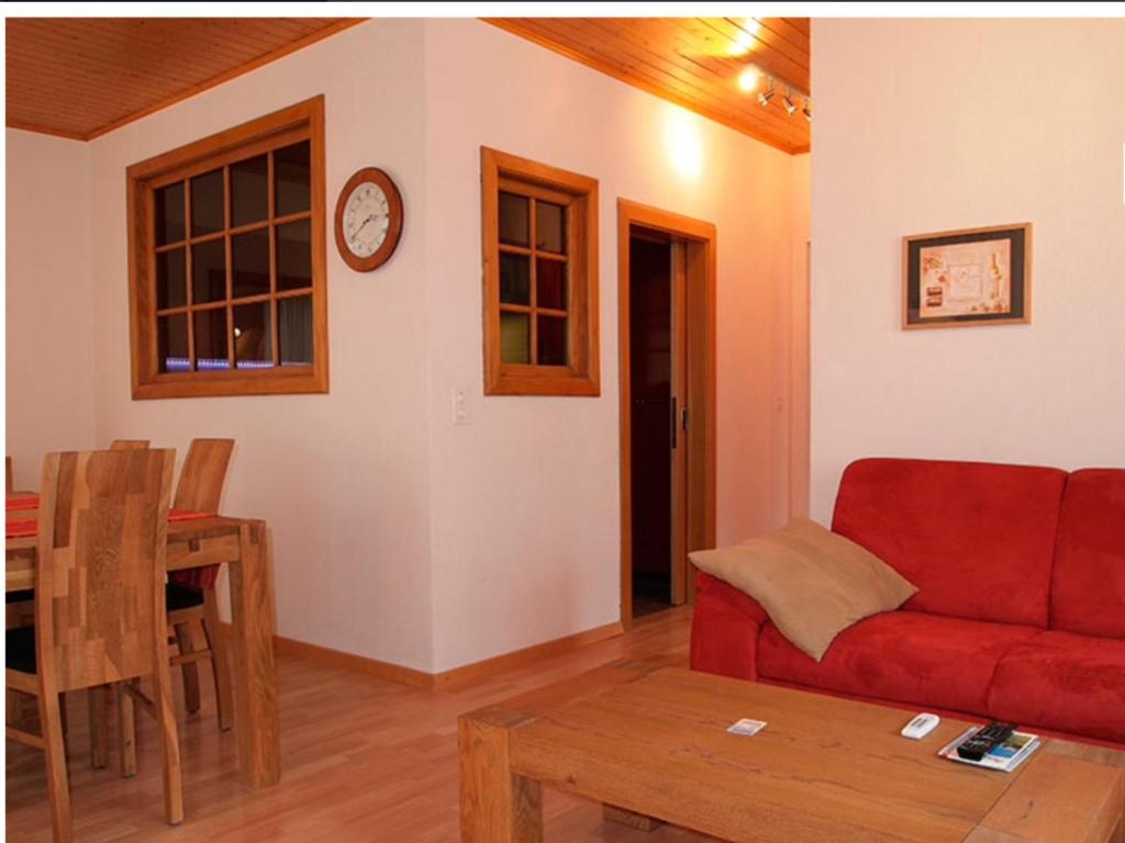 een woonkamer met een rode bank en een tafel bij Touring in Grächen