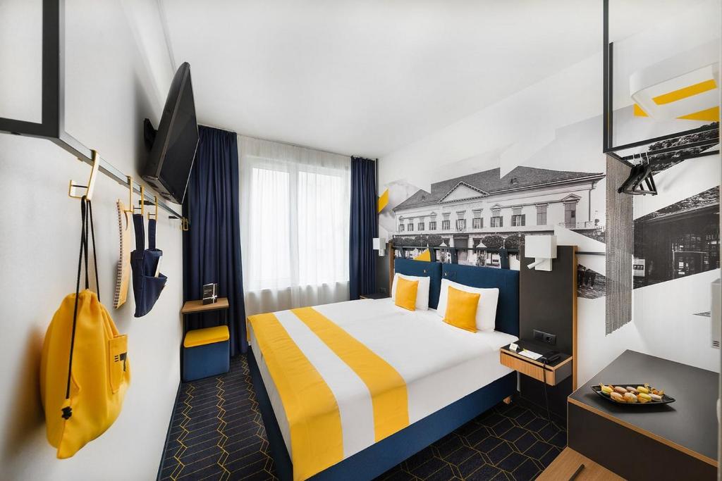 um quarto de hotel com uma cama com riscas amarelas e azuis em D8 Hotel em Budapeste