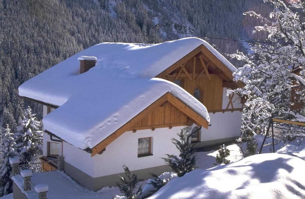 a building with snow on the roof of it at Apart Bel Ami in Kappl