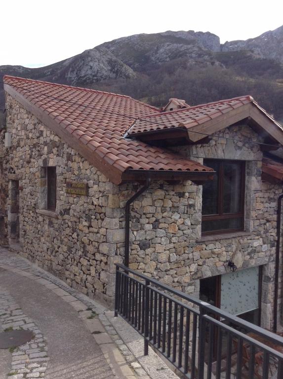 a stone building with a tile roof on a street at La Cabaña de Catalina in Sotres