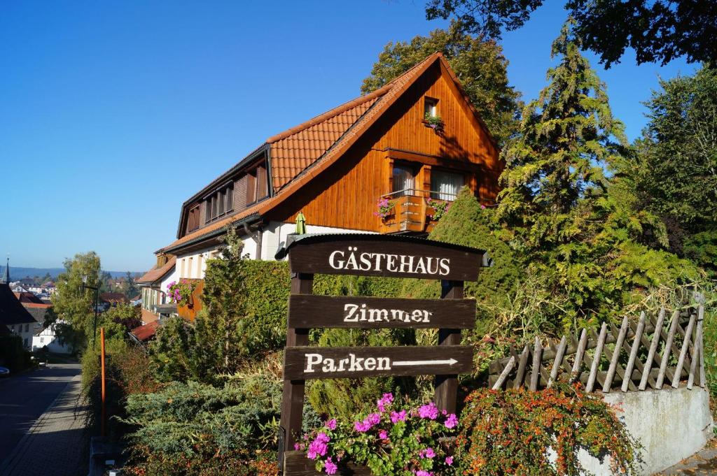 a sign in front of a house with a building at Pension Schüler in Bonndorf im Schwarzwald
