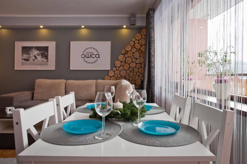 a dining room with a white table with blue plates and glasses at Czarny Potok 11/14 in Krynica Zdrój