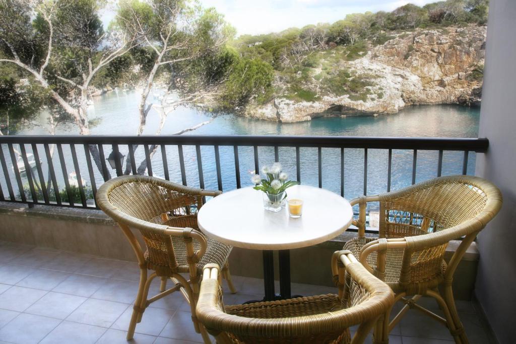 una mesa y sillas en un balcón con vistas al agua en Apartamentos Cala Figuera en Cala Figuera