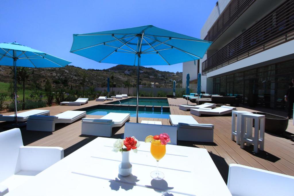 une terrasse avec une table, un parasol et une piscine dans l'établissement Hôtel Souani ( Al Hoceima Bay), à Al Hoceïma