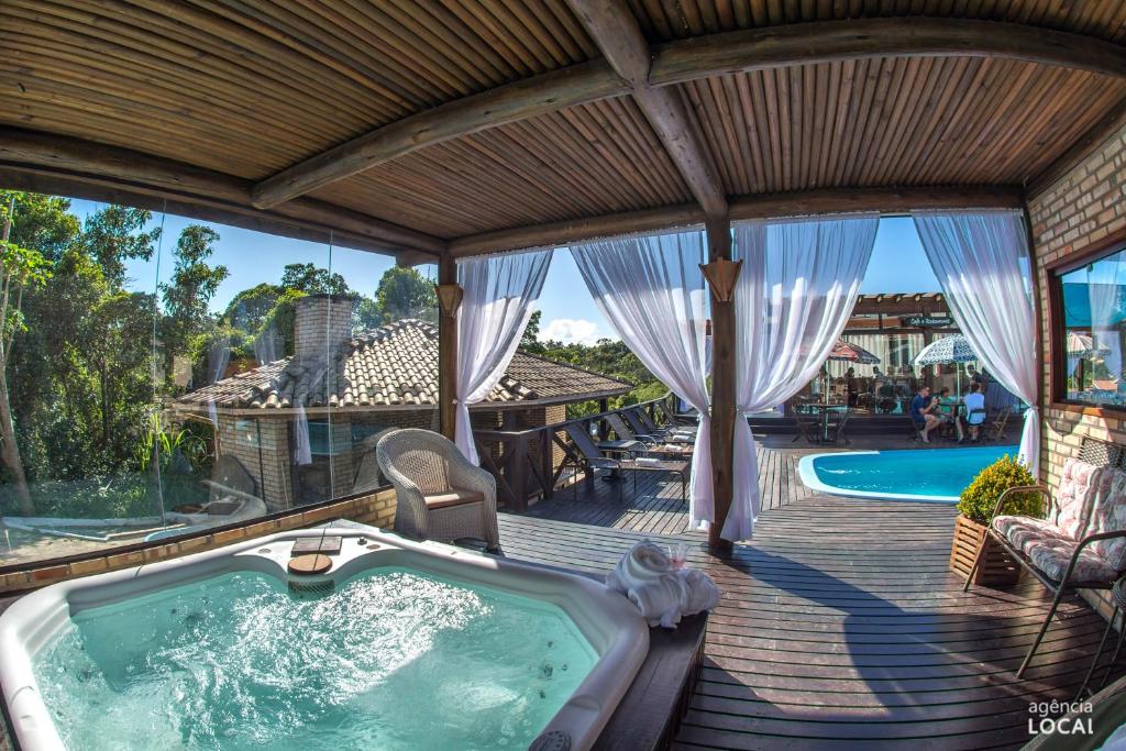 an outdoor deck with a hot tub and a pool at Pousada Natribus Rosa in Praia do Rosa