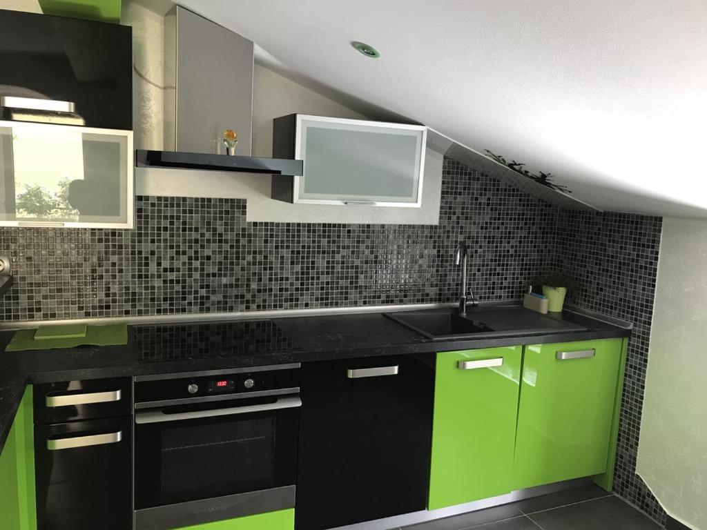 a kitchen with green and black cabinets and a sink at Apartma Marisol in Izola
