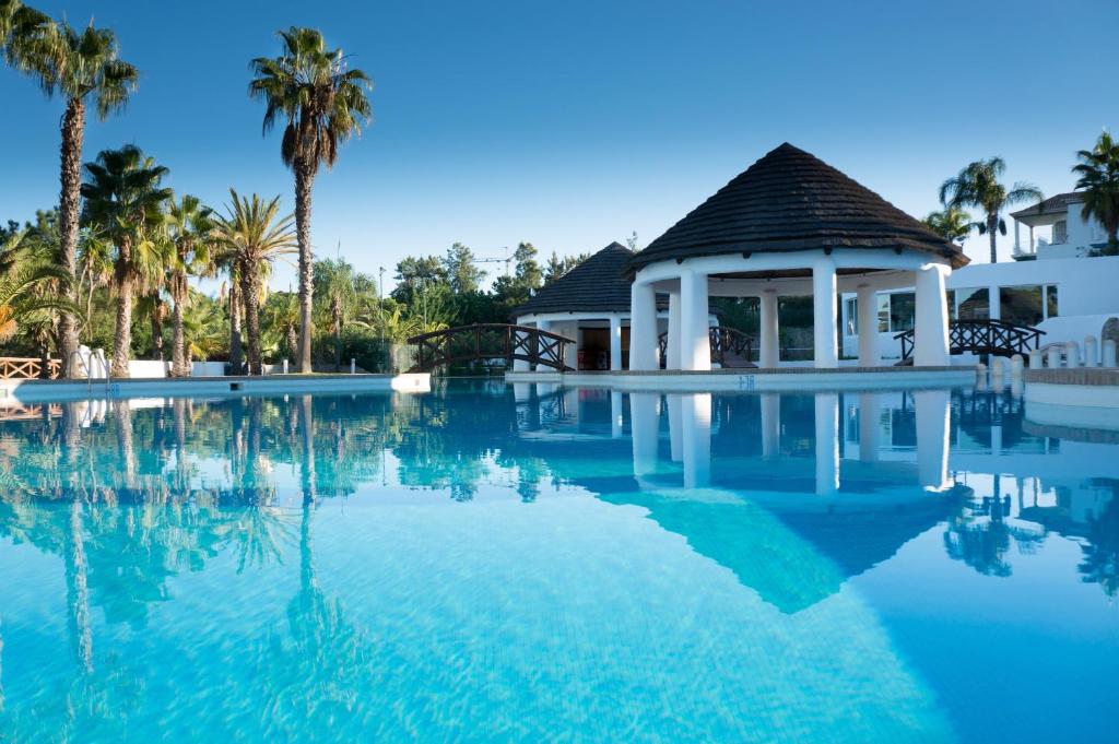 a swimming pool with a gazebo and palm trees at Apartamento Jarro in Quinta do Lago