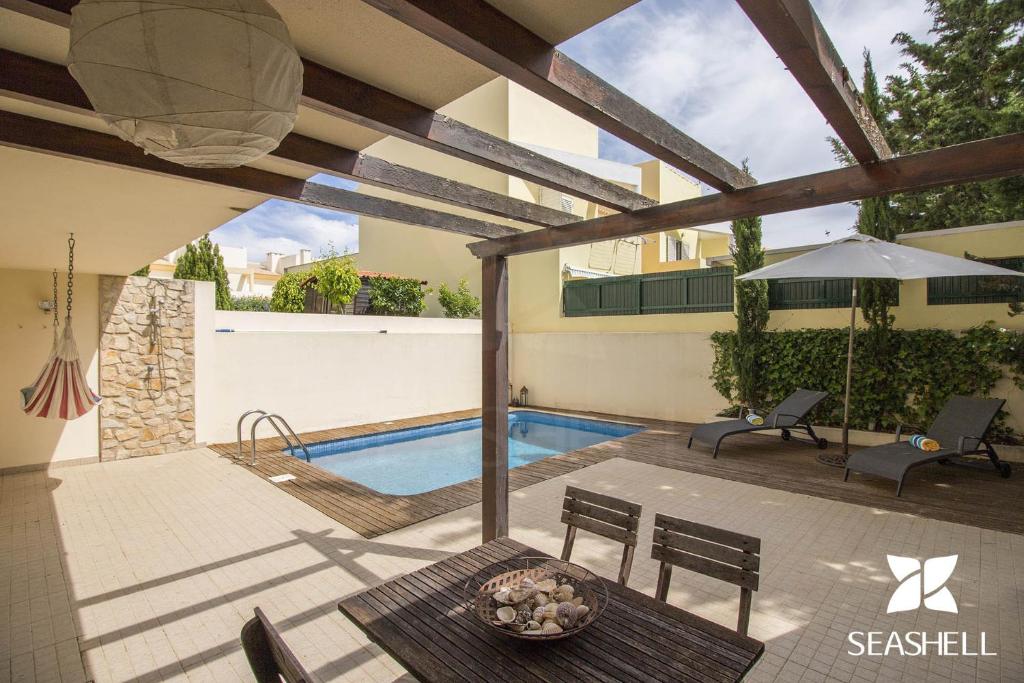 eine Terrasse mit einem Pool, einem Tisch und Stühlen in der Unterkunft Casa Oliveira in Loulé