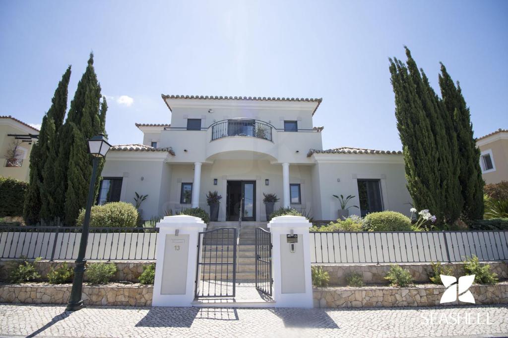 una casa blanca con una valla y árboles en Villa Esmeralda, en Almancil