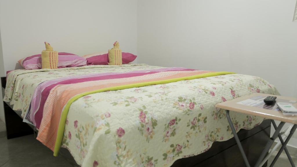 a bed with a floral blanket and a table at Inn Bless Aparthotel in San Andrés
