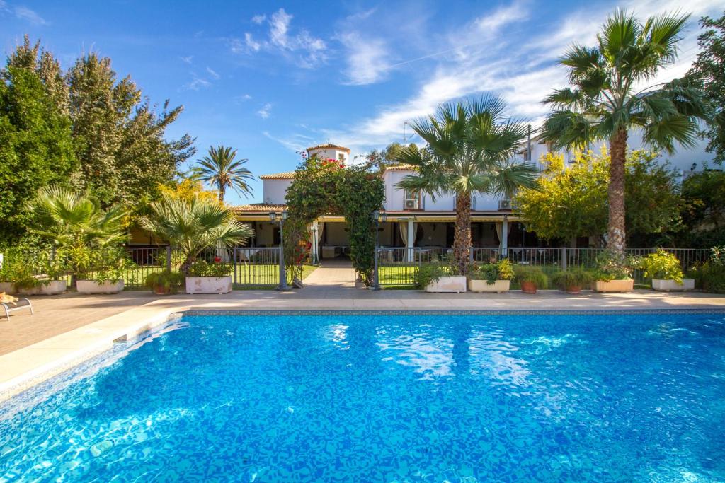 a swimming pool in front of a house with palm trees at Hotel Tossal d'Altea in Altea