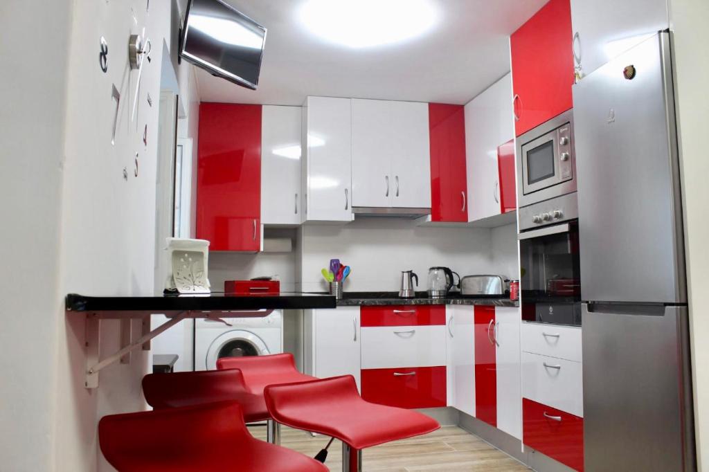 サンティアゴ・デ・コンポステーラにあるApartamento Casco Históricoの赤と白のキャビネットと赤のスツール付きのキッチン