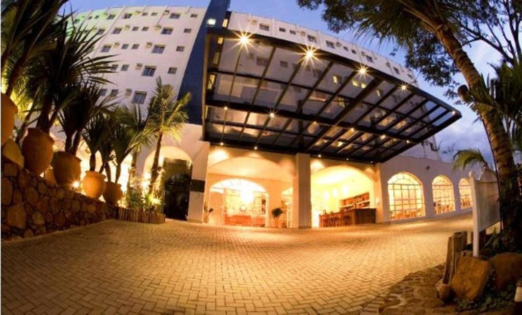 a large building with a building with palm trees in front of it at Beira Rio Palace Hotel in Piracicaba