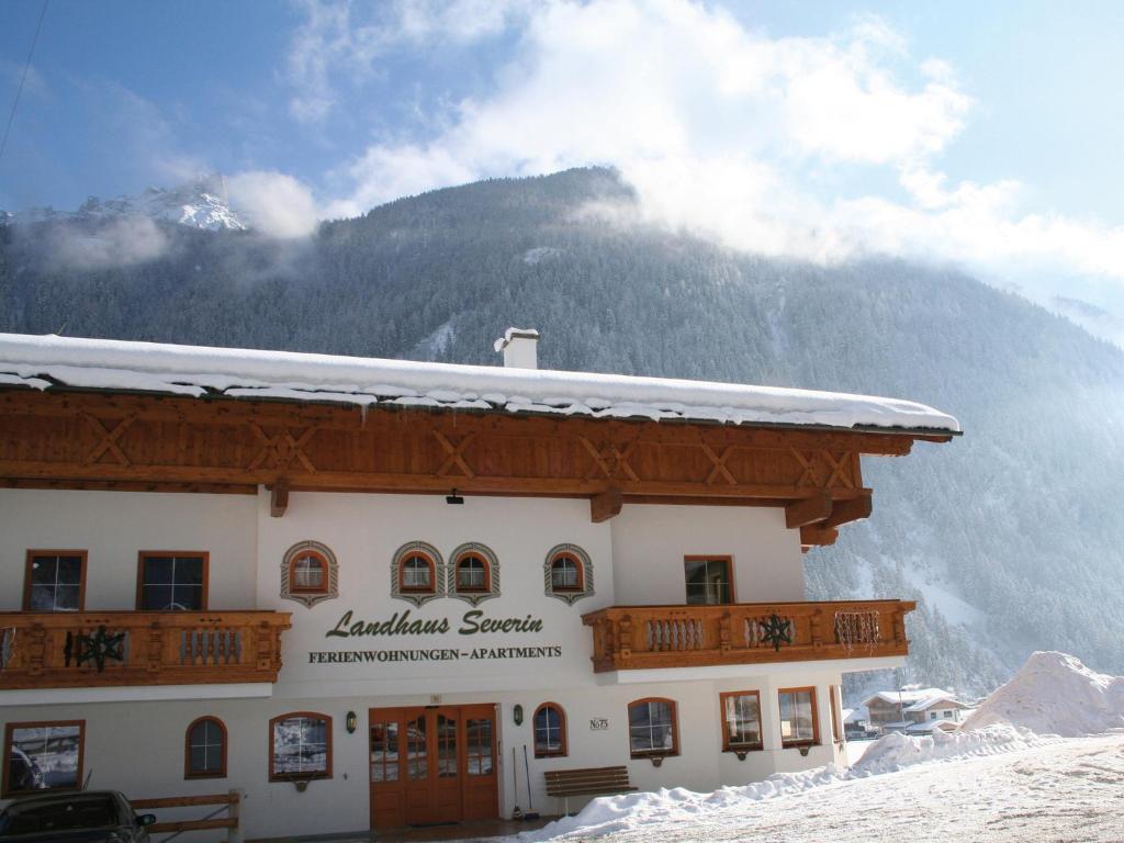 a building with a snow covered roof in front of a mountain at Landhaus Severin in Neustift im Stubaital