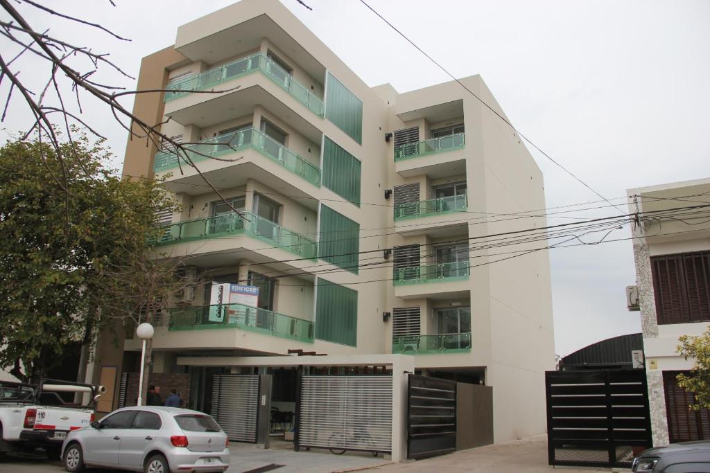 un edificio con balcones y coches estacionados frente a él en ALTA VISTA APART HOTEL en Reconquista