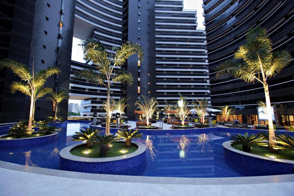 una piscina con palmeras frente a edificios altos en Landscape Residence by Escala Imóveis en Fortaleza