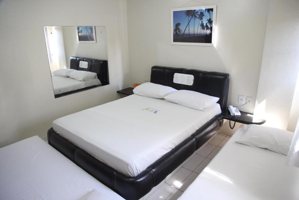 a small bedroom with two beds and a mirror at Hotel Piramide Pituba - Rua Pernambuco in Salvador