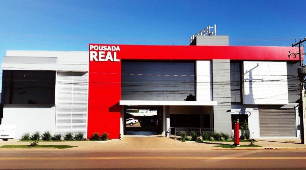 a red and white building with a red sign on it at Hotel Pousada Real in Sinop