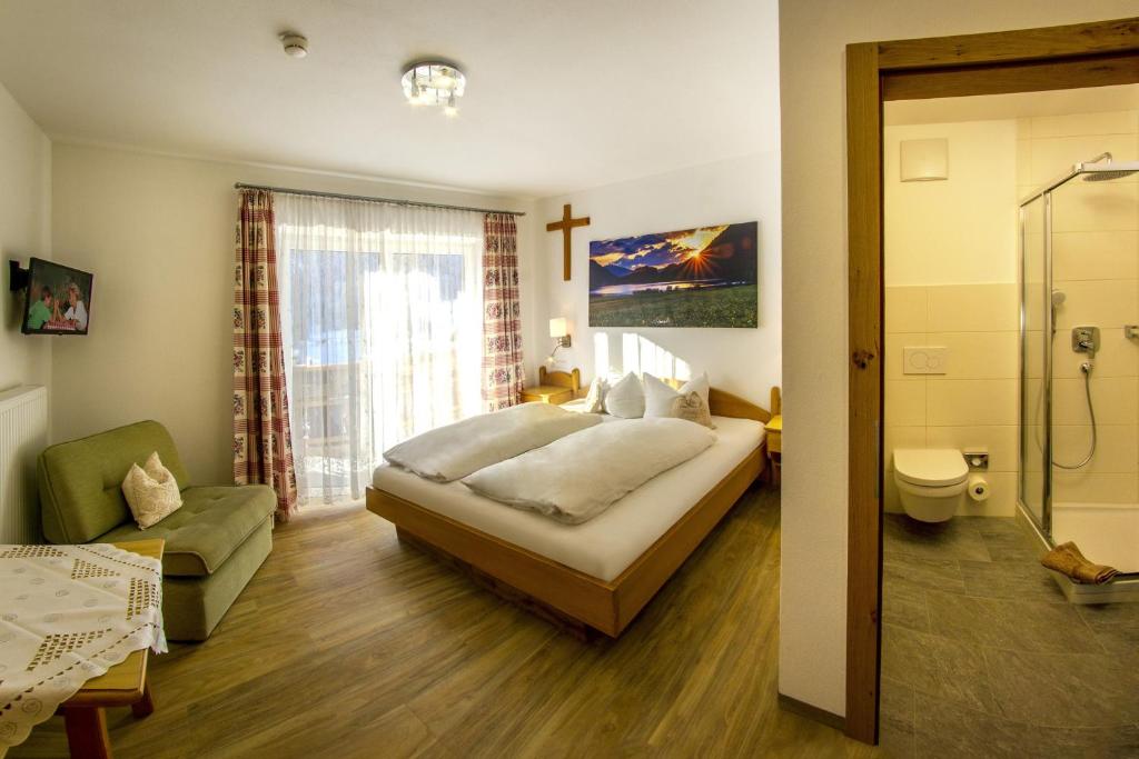 ein Schlafzimmer mit einem Bett und ein Badezimmer mit einer Dusche in der Unterkunft Haus Mariandl in Nesselwängle