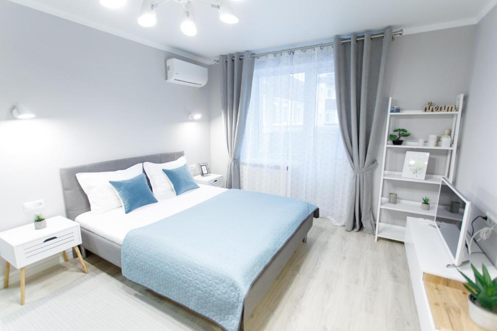 a white bedroom with a bed and a window at Apart-Hotel "LAVINA" in Sumy