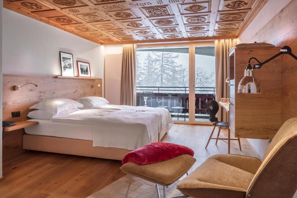 a bedroom with a bed and a desk and a window at Swiss Alpine Hotel Allalin in Zermatt