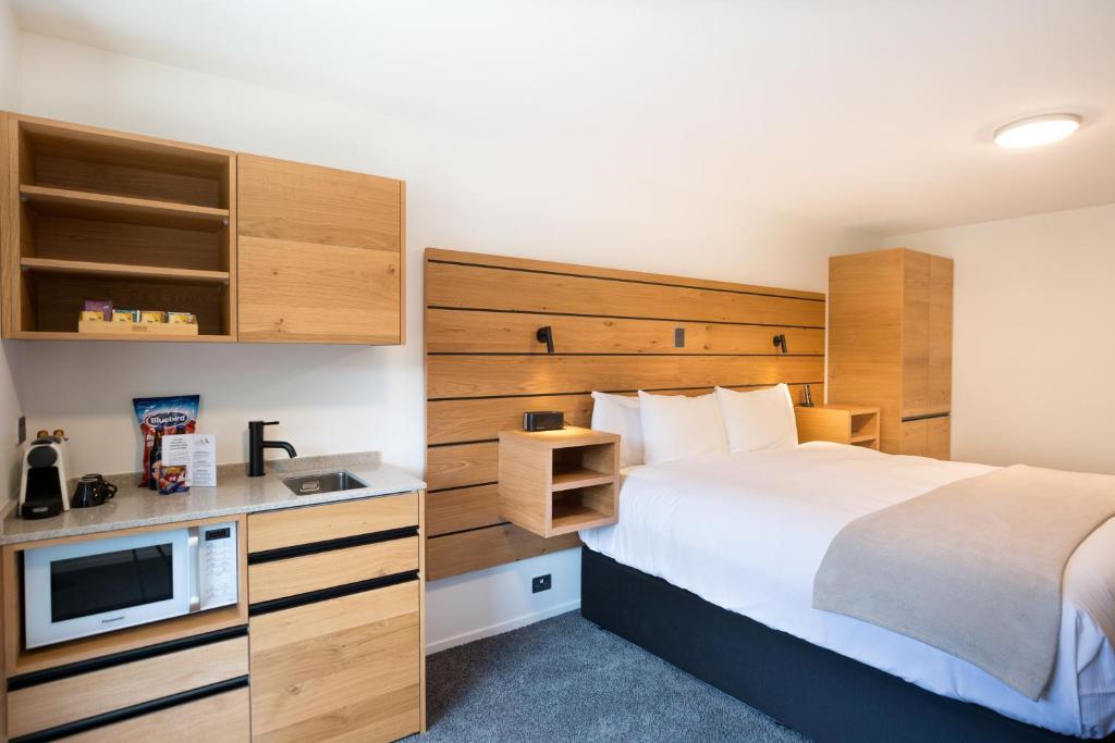 Una habitación de hotel con una cama y un televisor. en Lomond Lodge Motel & Apartments, en Queenstown