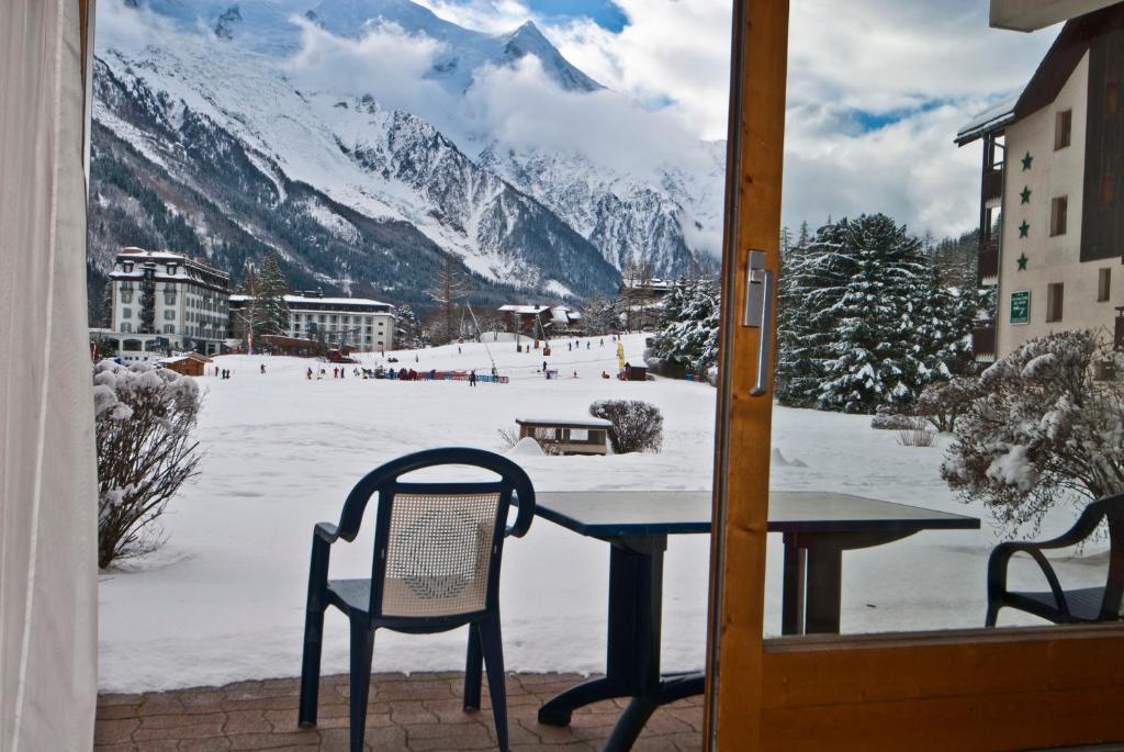una mesa y sillas en un balcón con una montaña nevada en Front Ski Slope Chamonix Apartment, en Chamonix-Mont-Blanc
