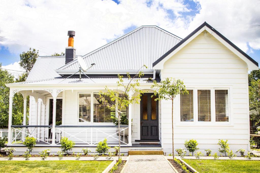 una casa bianca con una porta nera di White Cottage a Matakana