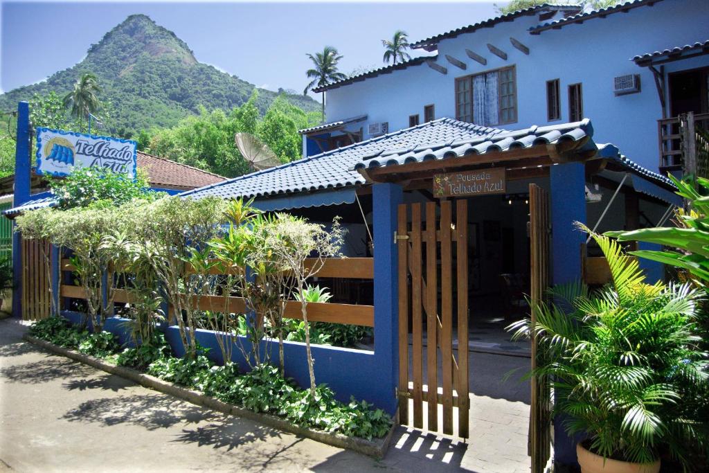 a building with a gate and a mountain in the background at Pousada Telhado Azul in Abraão
