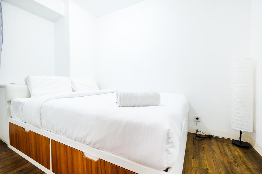 - une chambre avec un lit blanc et du parquet dans l'établissement Modern and Comfy 3BR Bassura City Apartment By Travelio, à Jakarta