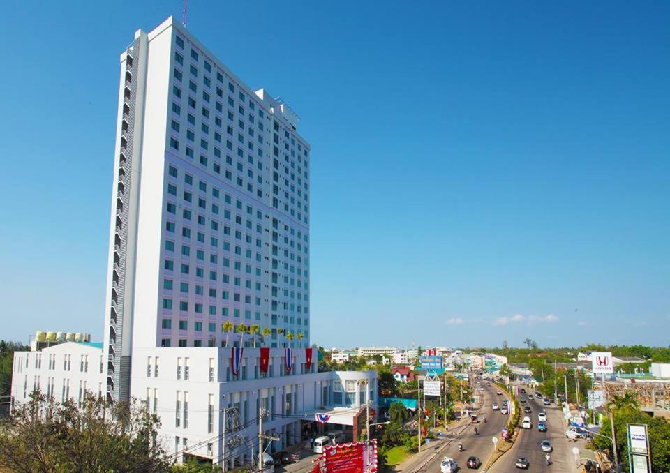 un edificio blanco alto junto a una concurrida calle de la ciudad en Diamond Plaza Hotel, en Suratthani