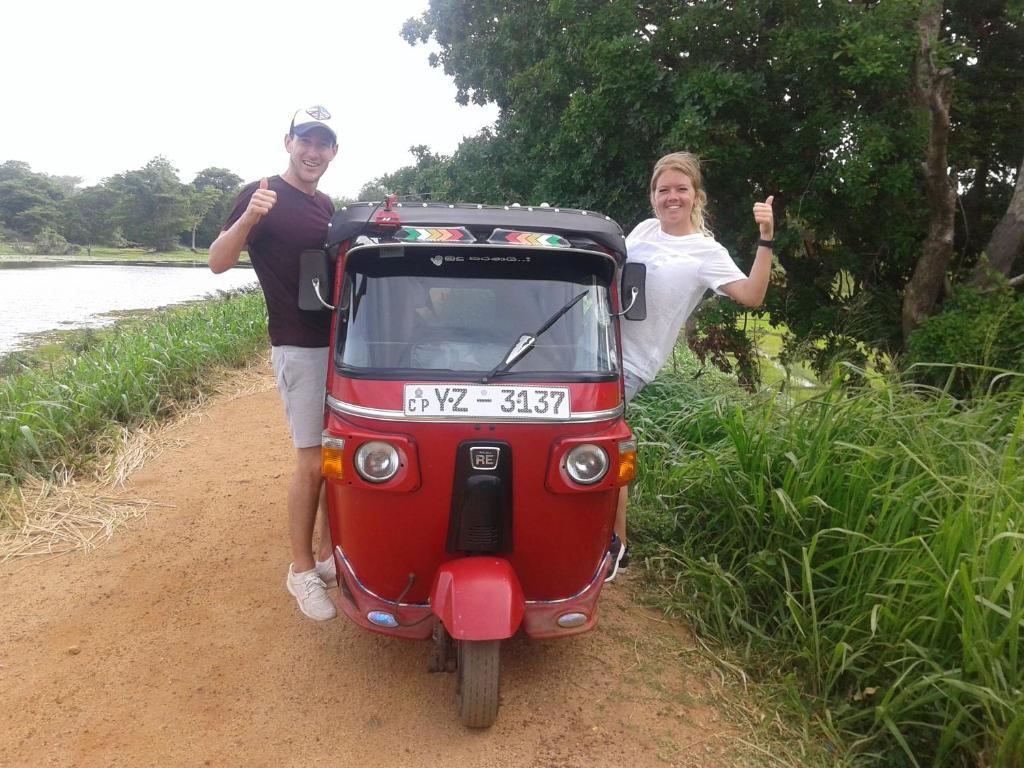 a man and a woman standing next to a small motor scooter at Sigiri Anu Homestay in Sigiriya