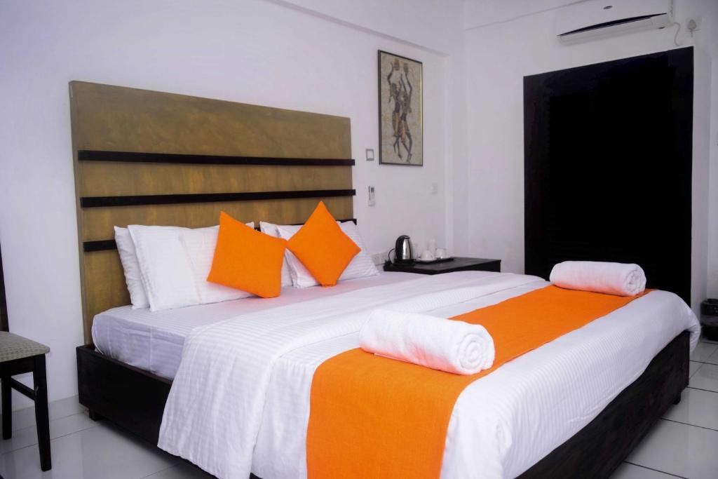2 camas con sábanas naranjas y blancas en una habitación en 360 Beach Residence en Negombo