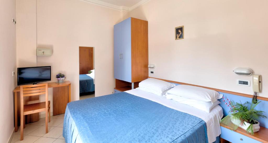 - une chambre avec un lit bleu et une télévision dans l'établissement Hotel Roby, à Riccione