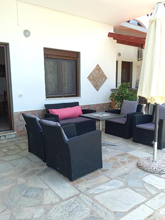 a patio with couches and a table and a umbrella at Pelagos Beachfront in Panormos Skopelos