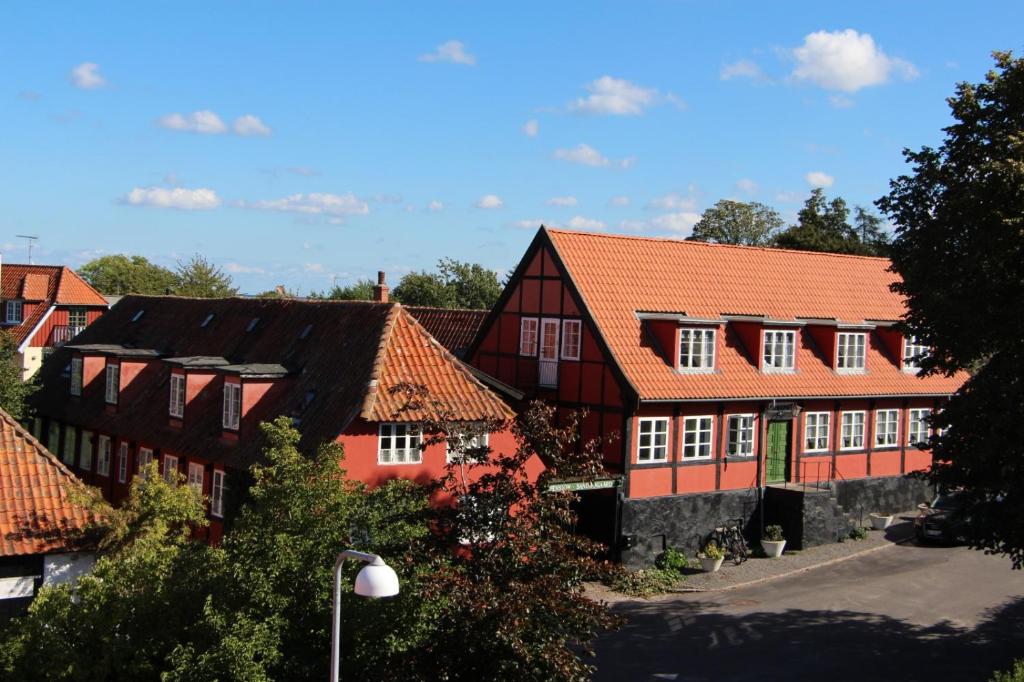 een rij rode gebouwen met oranje daken bij Pension Sandbogaard in Sandvig