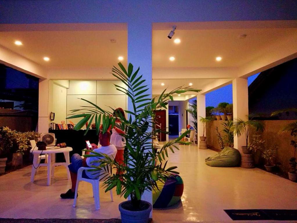 a man sitting at a table in a house with a plant at Eden Blue Hikkaduwa in Hikkaduwa